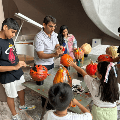 A family painting terracotta pumpkins together at a Kitsters workshop